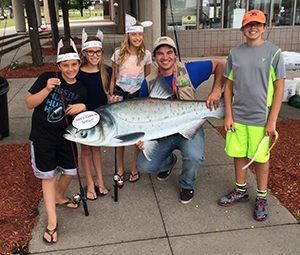 kids in fish hats pose with DNR staffer holding large fish cutout