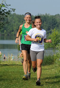 two female runners with lake and woods in background