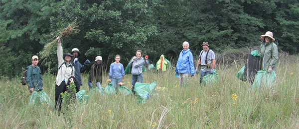 Group of park stewardship volunteers with garbage bags in field