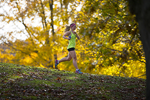 woman running through wooded area with fall colors