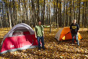 two men beside tents in fall forest