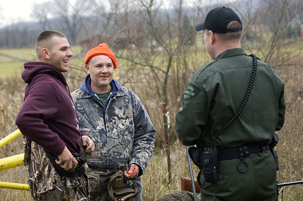 A conservation officer talks with two hunters.