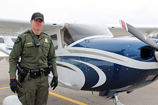 A conservation officer stands in front of a plane used for "bait flights."