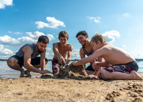 group of young men building sandcastles on beach