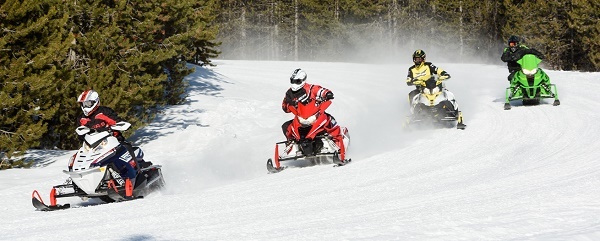 four snowmobilers coming around a curve in the trail