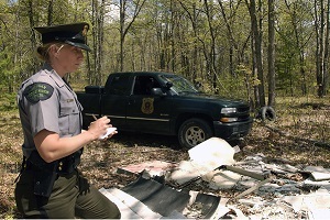A female conservation officer writes up a report on a dumping site, part of the Adopt a Forest program