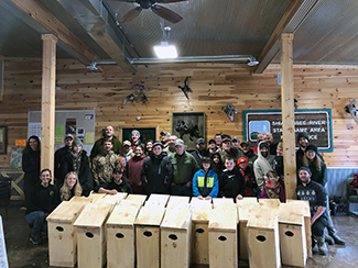 A group of volunteers poses for a photo with the wood duck boxes they built.