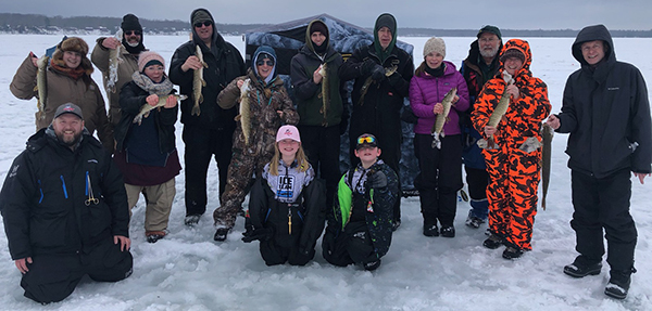 Group of people om frozen lake holding fish