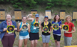 Group of teachers holding targets with shot marks at shooting range