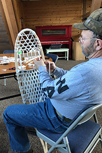 man sitting in chair making a snowshoe