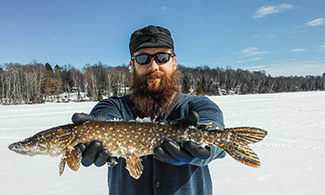A man displays a northern pike he caught while ice fishing.