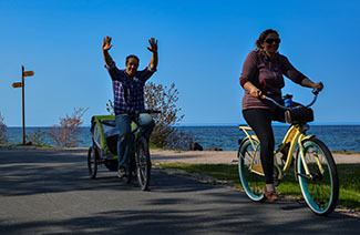 A couple rides their bikes along a shady section of the Iron Ore Heritage Trail.