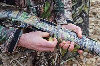 A turkey hunter gets ready to load a shell into his shotgun.