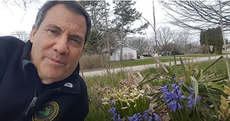 A Michigan Department of Natural Resources educator is pictured with a flowery spring scene in the photo.
