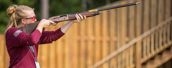 woman aiming shotgun at clay target