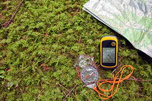 Map, GPS unit and compass on the ground