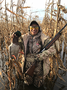 female waterfowl hunter in wetland holding duck