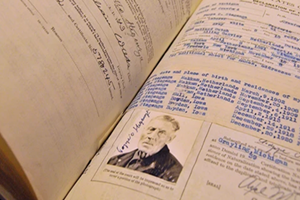 An open ledger features a photo of a man and handwritten script