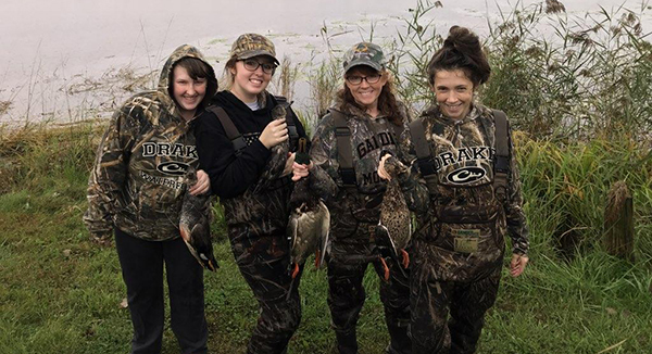 Group of young female hunters holding harvested ducks