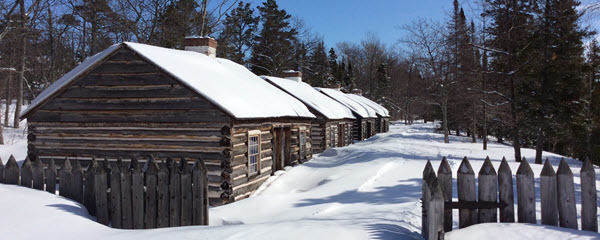 A row of log cabins covered in snow.