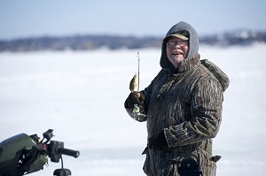 Man ice fishing and holding up his catch