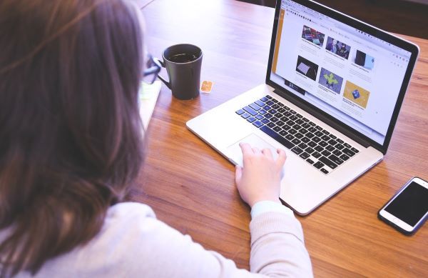 A woman is seen using a laptop computer with a series of apps open