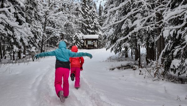 Two kids in bright snow gear play in a winter wonderland