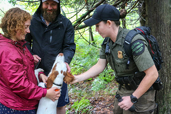 Michigan Conservation Officer Amanda McCurdy meets two people and their dog who were walking a trail.