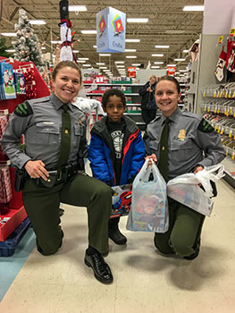 Michigan Conservation Officers Anna Cullen and Jackie Miskovich shop with a child during the 2019 Shop with a Cop effort 