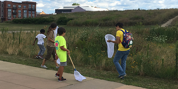 group of kids with butterfly nets on edge of field in urban area