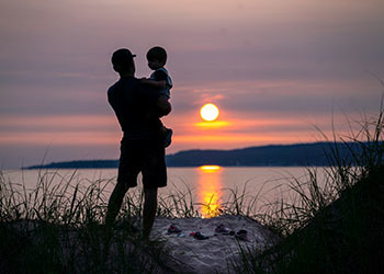 man standing on dune holding child