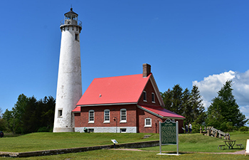 Tawas Point Lighthouse is whitewashed with an attached red brick and red roofed keeper's quarters