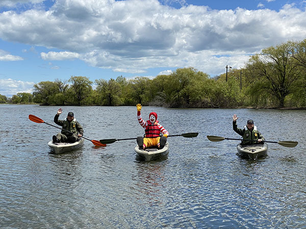 Conservation Officers and Ronald McDonald on a boat wearing life jackets