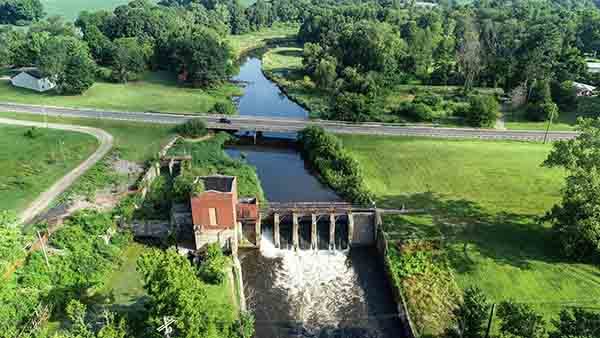 An aerial photo shows the Pucker Street Dam prior to dismantling within lush, green surroundings in this springtime photo.