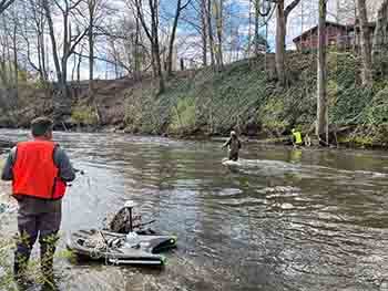 Workers in the Dowagiac River string a rope across a transect to allow a boat to move across a monitoring site.
