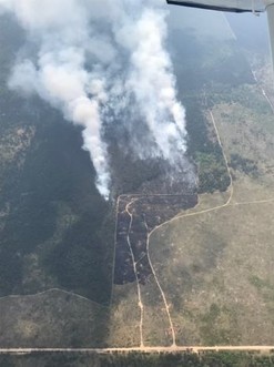 Smoke billows out of a blackened area of land in an aerial photo of the wildfire 