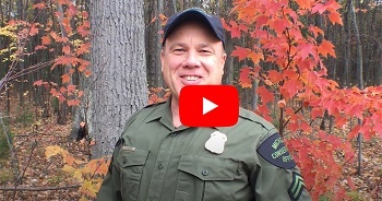 Video thumbnail play button overlay on a smiling male conservation officer