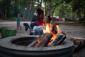 A woman and a child share a tender cuddling moment before a campfire at a Michigan state park.