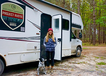 woman and dog standing by RV with Project Rustic logo