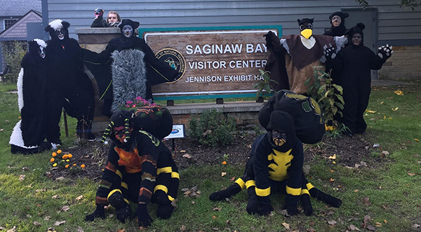 People in animal costumes by Saginaw Bay Visitor Center sign