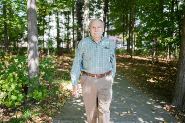 Image of garden director Frank Telewski on a path surrounded by trees and vegetation