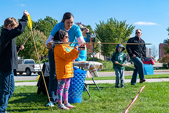 Participants in Archaeology Day are shown using an atlatl, which aids in spear throwing.