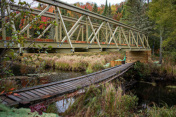 A newly built, elevated boardwalk is shown perched above the old trail footbridge at Craig Lake State Park.