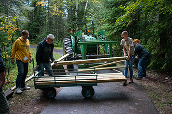 Michigan Cares for Tourism volunteers load bridge timbers at the Bond Falls Scenic Site.