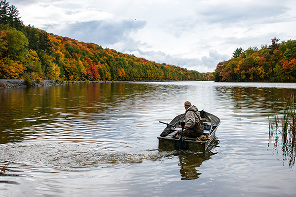 A hunter and his dog motor out in a boat on the waters of Goose Lake to hunt ducks. 