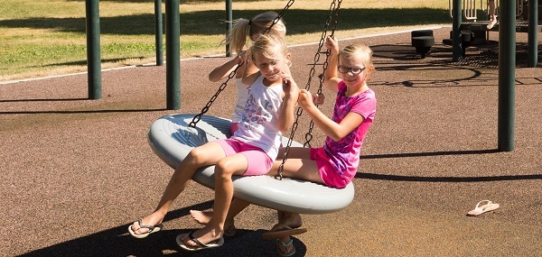 three little blond-haired girls swinging on a tire swing