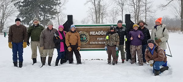 Group of volunteers by Fort Custer Recreation Area sign in winter
