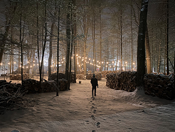 person walking through snowy path between lights