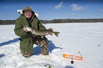 Man holding pike on frozen lake