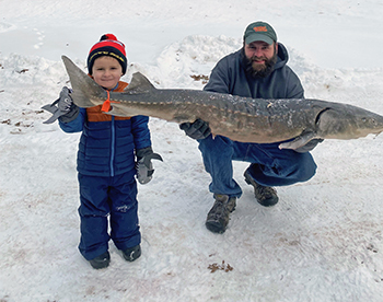 A father and son display their huge sturgeon catch on Black Lake.